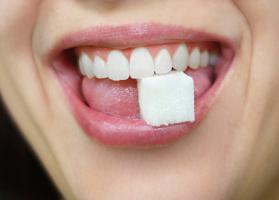 smiling woman biting a sugar cube